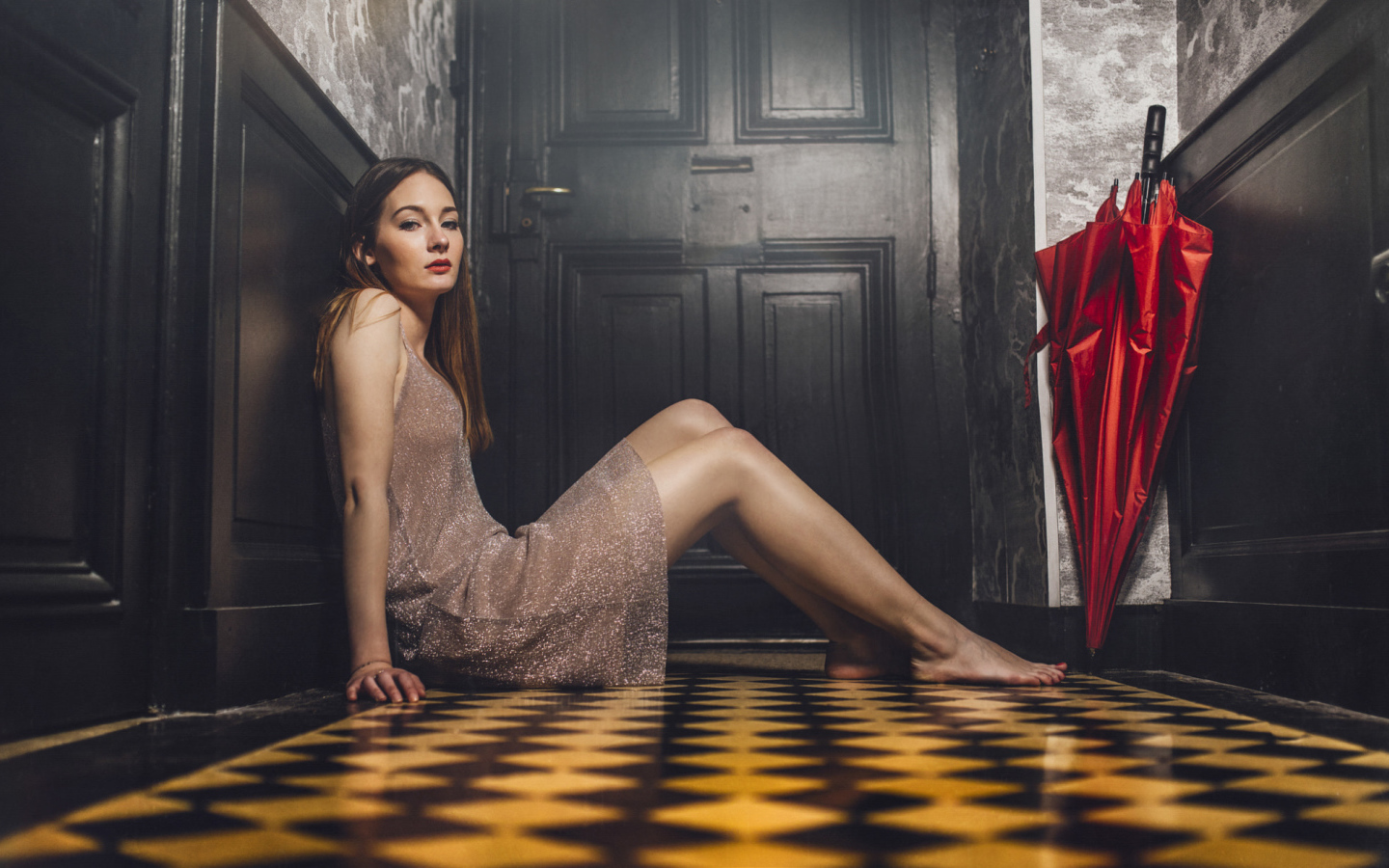 Красивая девушка модель с красным зонтом сидит на полу