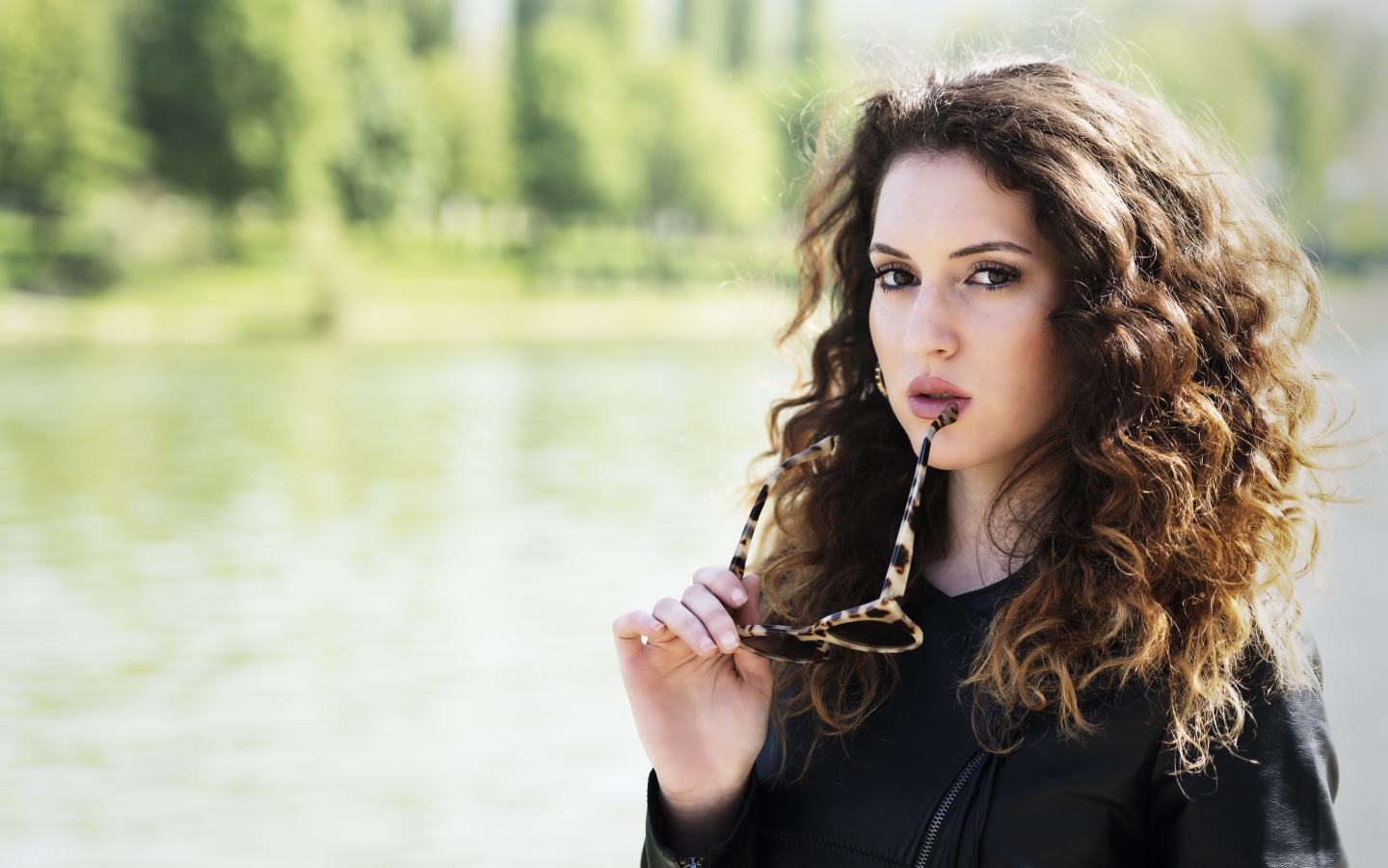 Красивая девушка с волнистыми волосами с очками в руках 