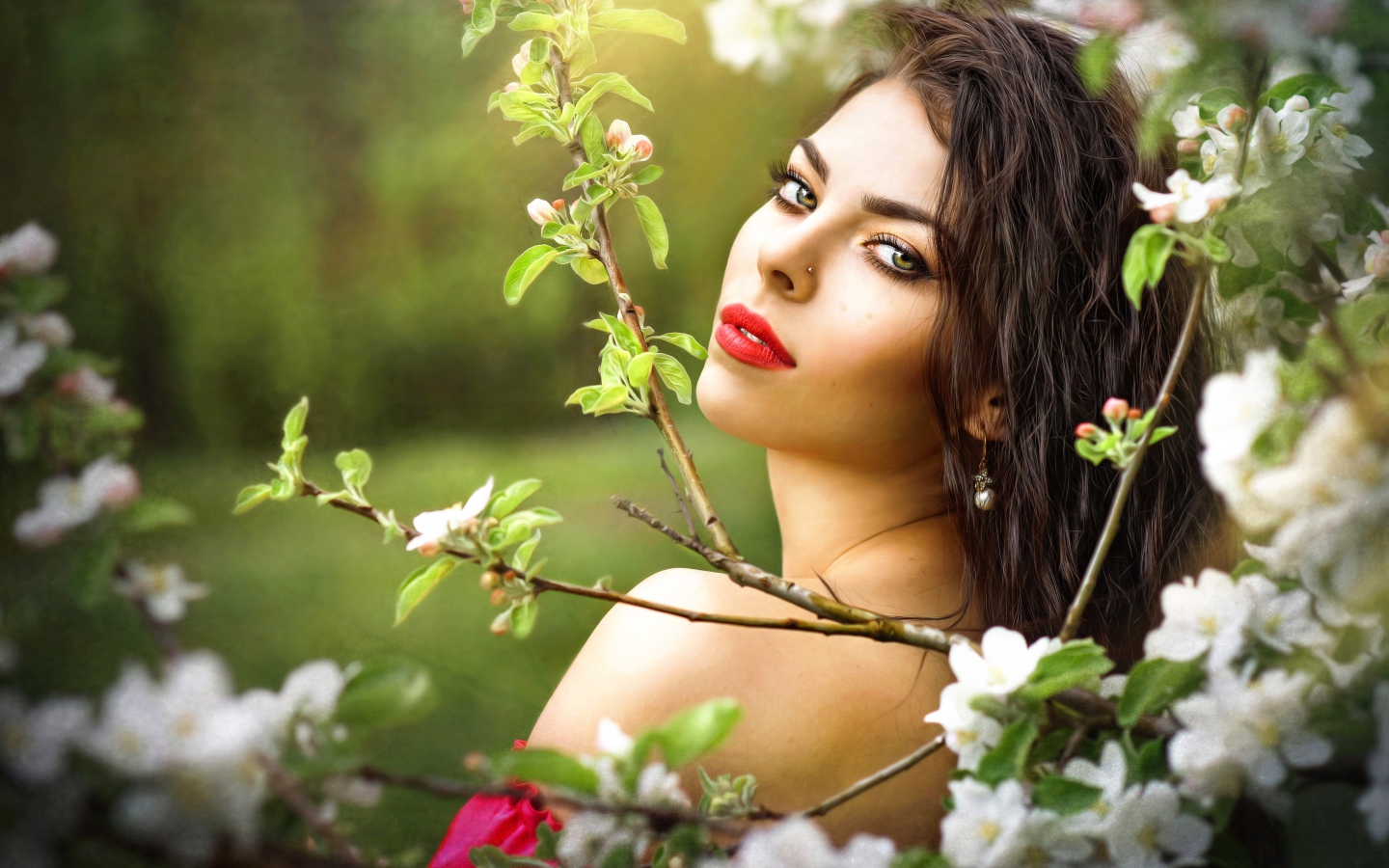 Красивая молодая девушка в ветках цветущей яблони 