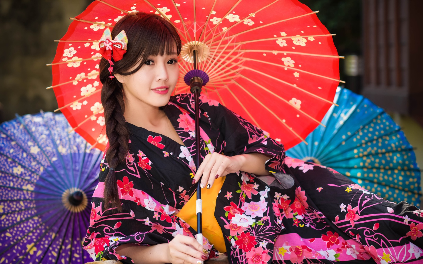 Молодая азиатка в кимоно с разноцветными зонтиками
