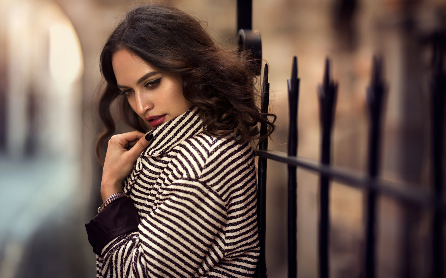 Молодая брюнетка в пальто у забора