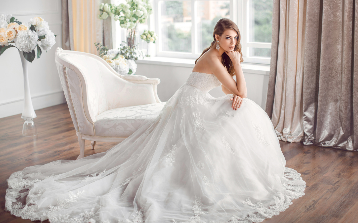 Молодая девушка в красивом свадебном платье сидит в белом кресле