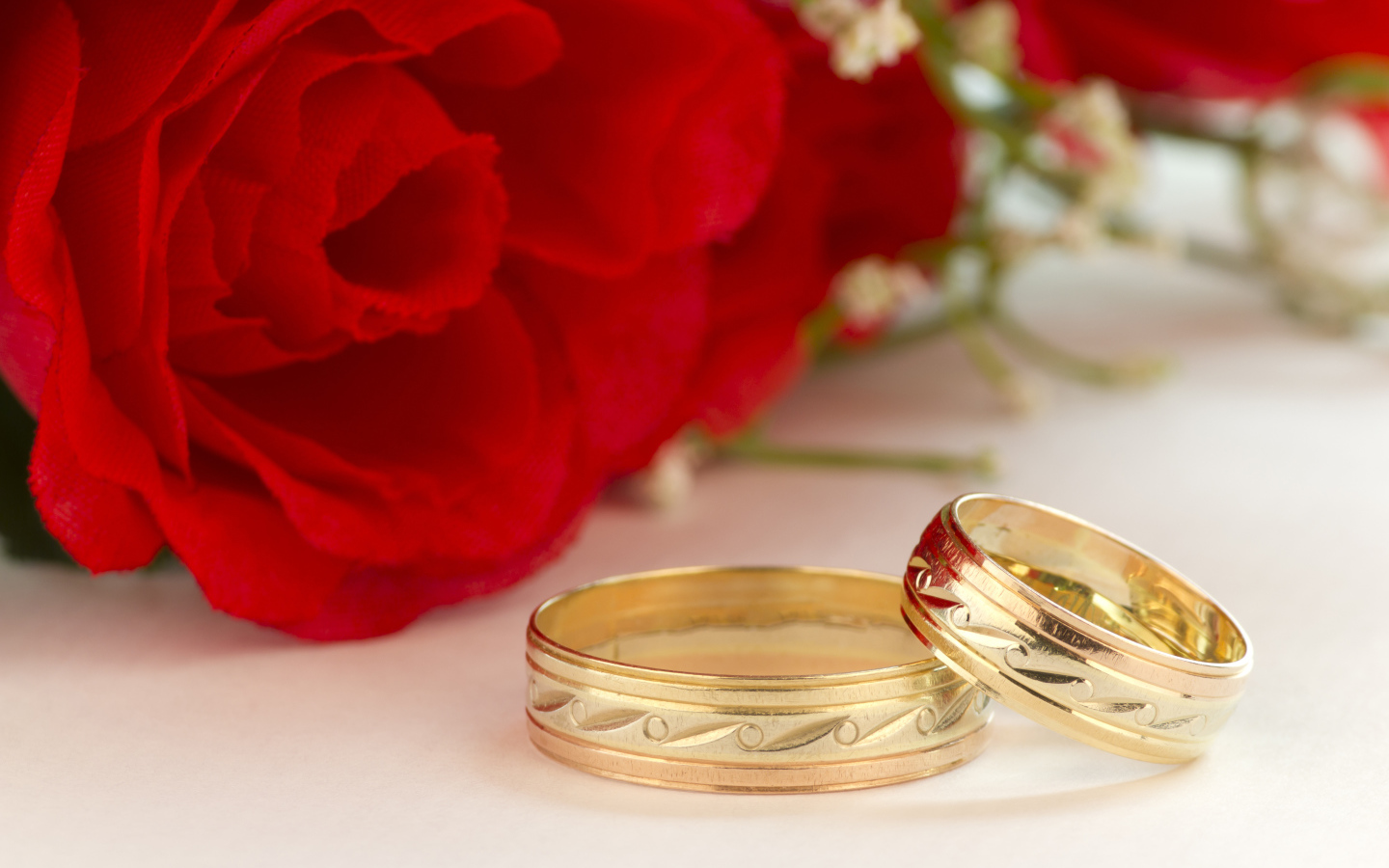 Золотые обручальные кольца с рисунком и красные розы на свадьбу