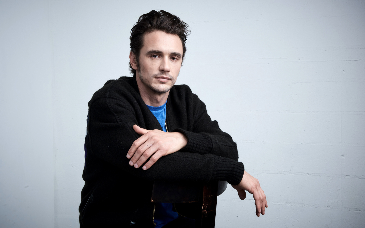 Актер Джеймс Франко в черной кофте на сером фоне