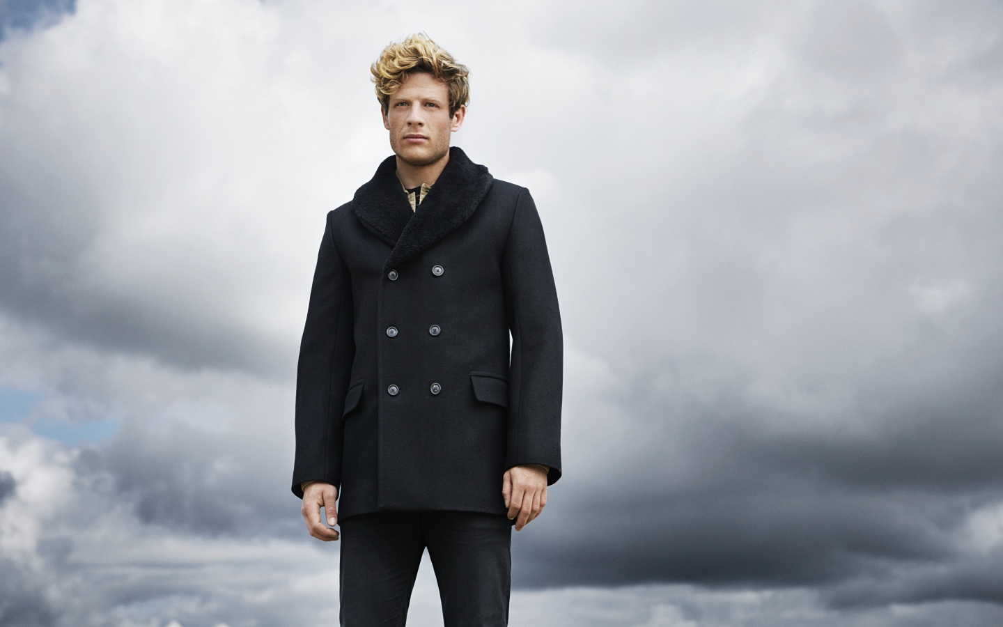 Актер Джеймс Нортон в черном пальто на фоне неба