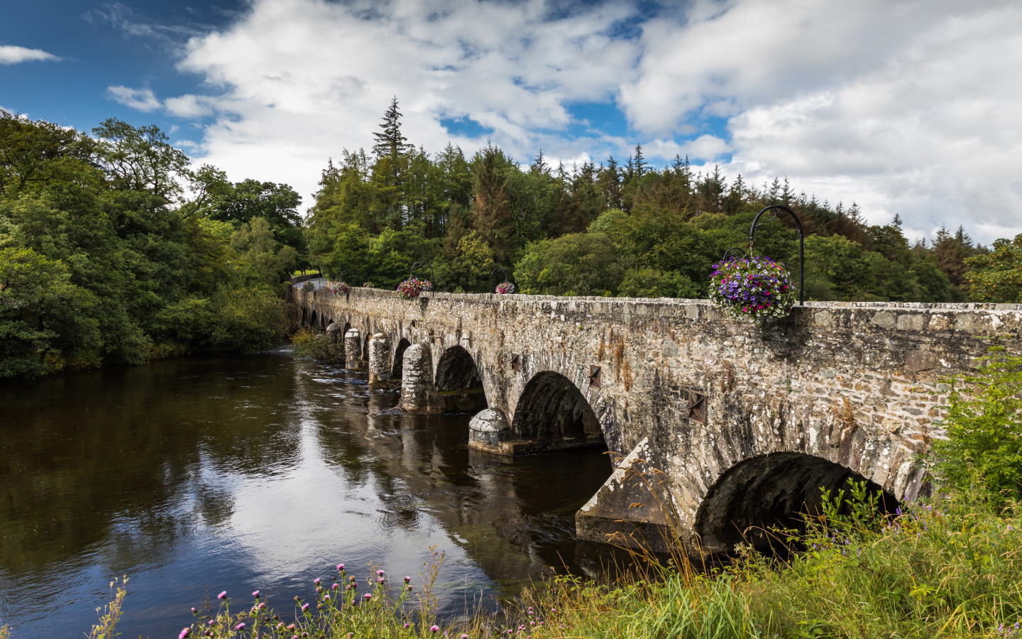 Мост через реку у леса на фоне красивого голубого неба с белыми облаками. Ирландия