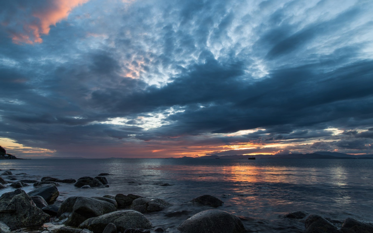Валуны в воде на берегу на фоне пасмурного неба 