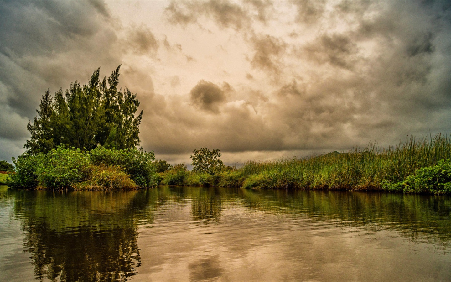 Облака над озером с покрыми зеленой травой берегами