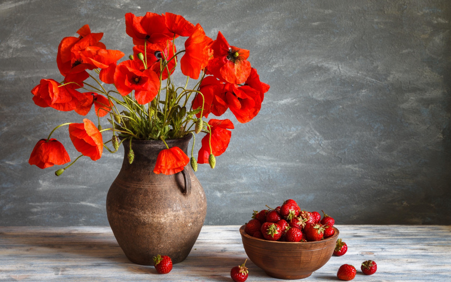 Красивый букет красных полевых маков в вазе на столе с клубникой