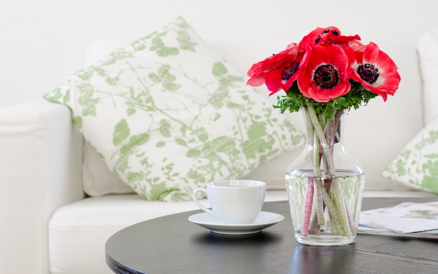 Букет красных цветов анемоны в вазе на столе с белой чашкой