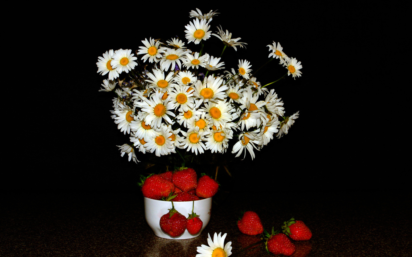 Белые полевые ромашки и клубника на столе на черном фоне