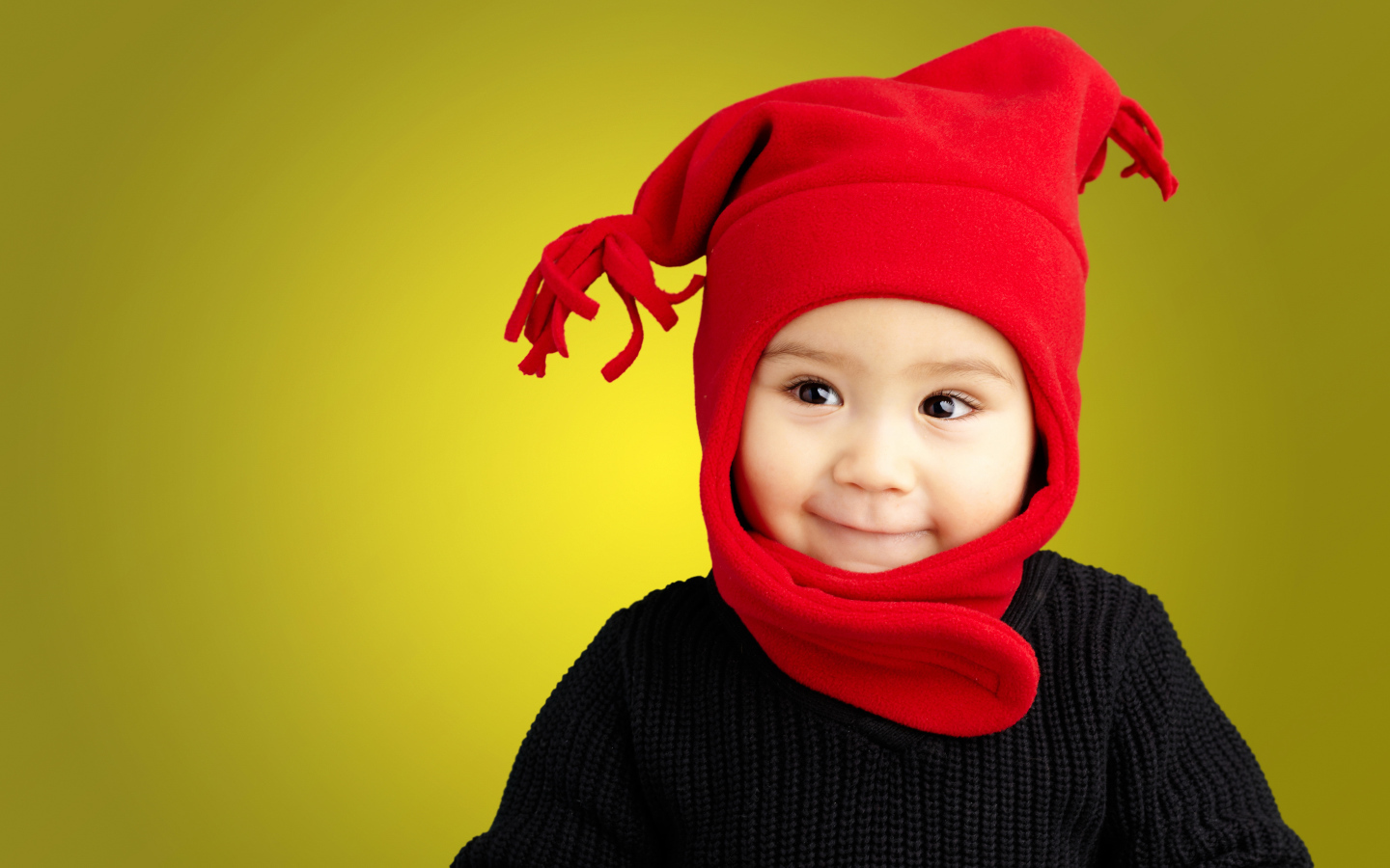 Маленький мальчик в красной шапке и в черном свитере