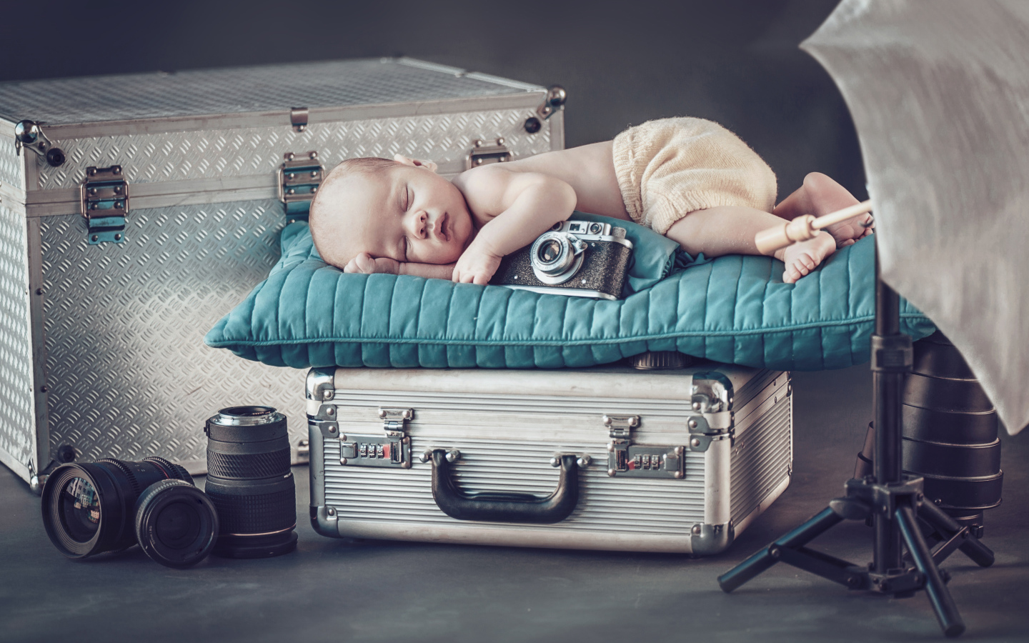 Спящий младенец с фотоаппаратом спит на чемодане