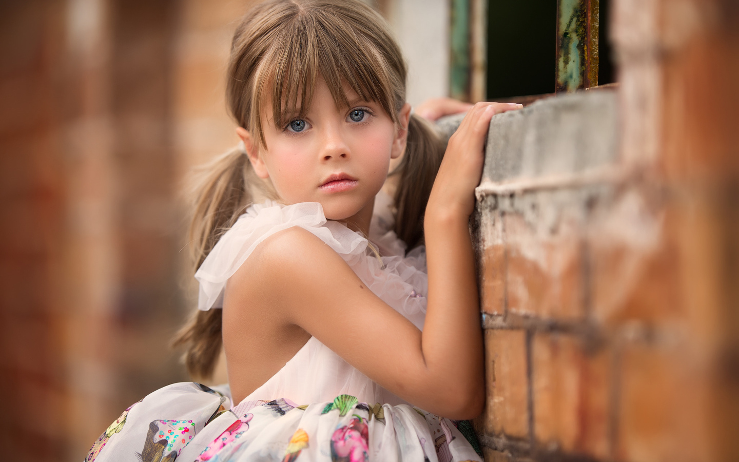 Милая девочка с серьезным взглядом стоит у стены