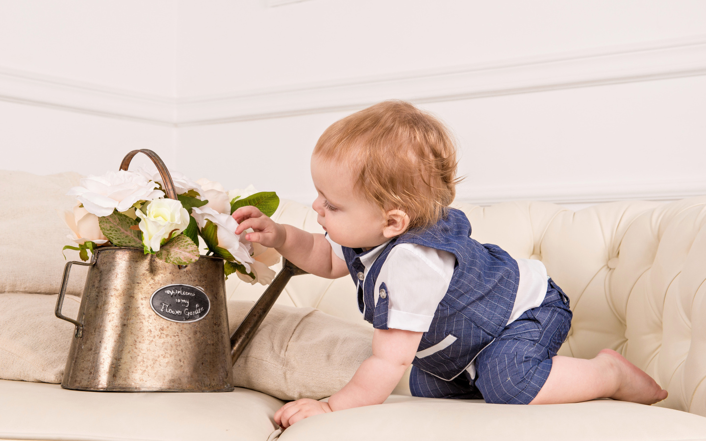 Маленький ребенок рассматривает цветы в железной лейке