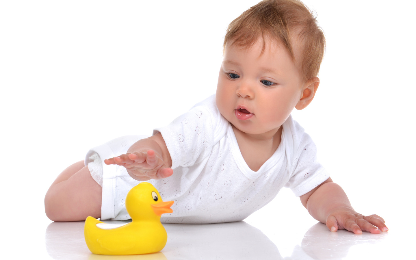 Грудной ребенок с желтой резиновой уточкой на белом фоне