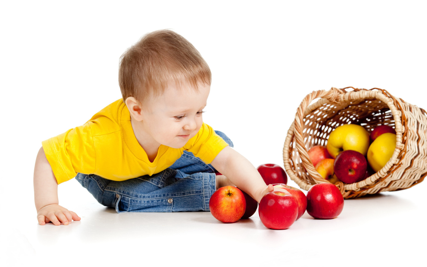 Маленький мальчик с корзиной спелых яблок на белом фоне