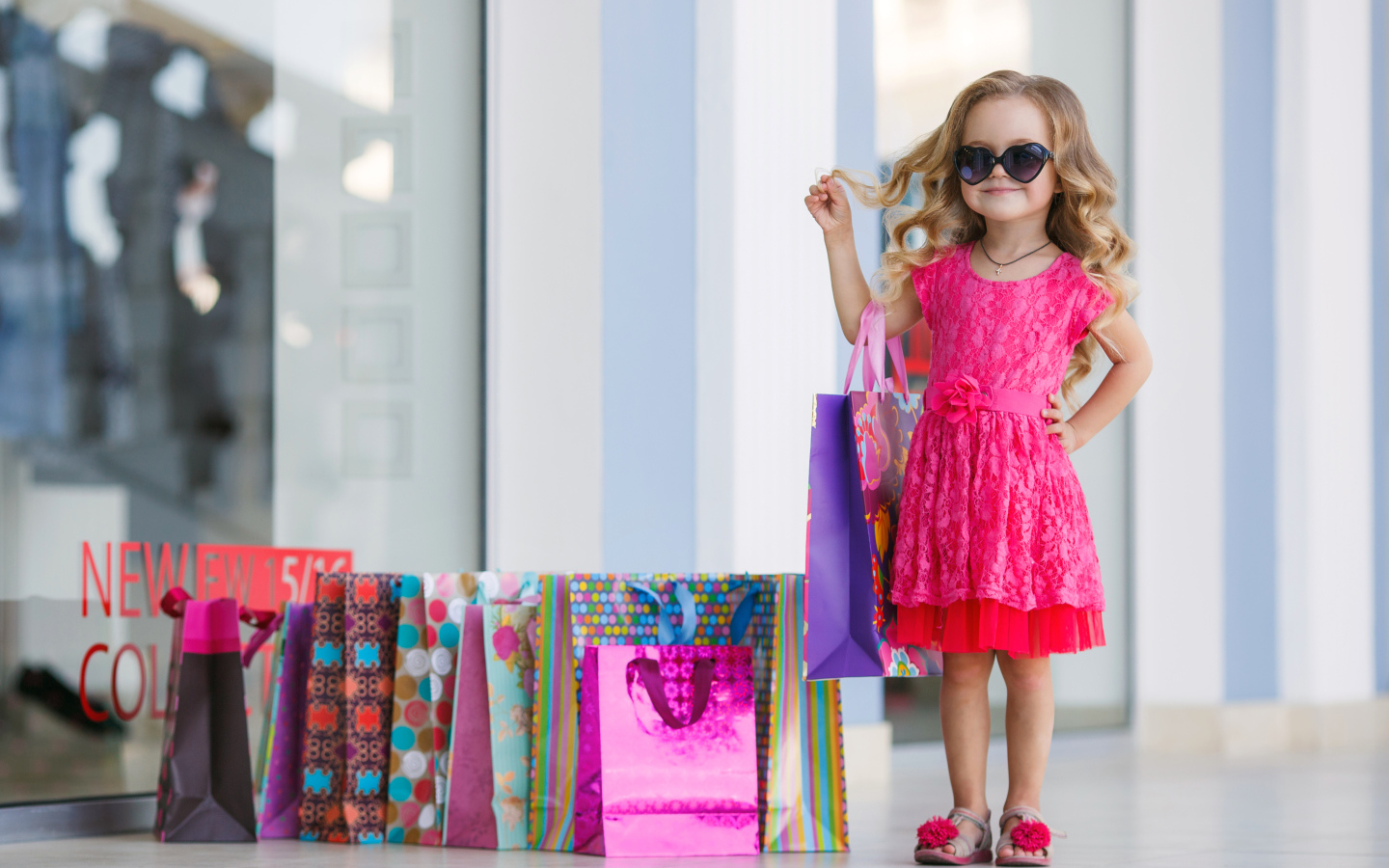 Маленькая модная девочка в красном платье с покупками