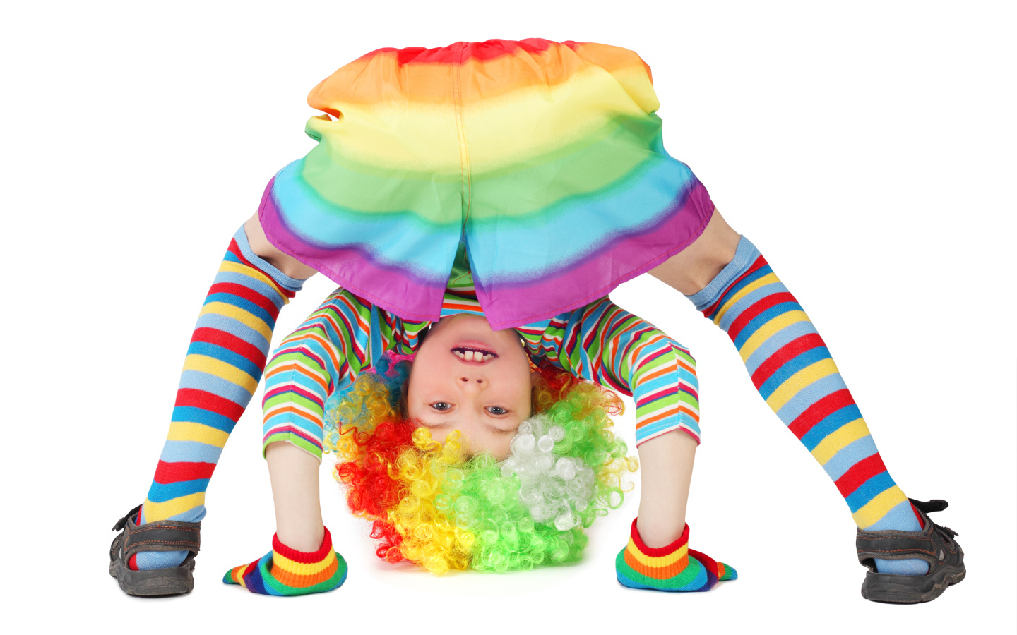 Маленькая смешная девочка в костюме клоуна на белом фоне