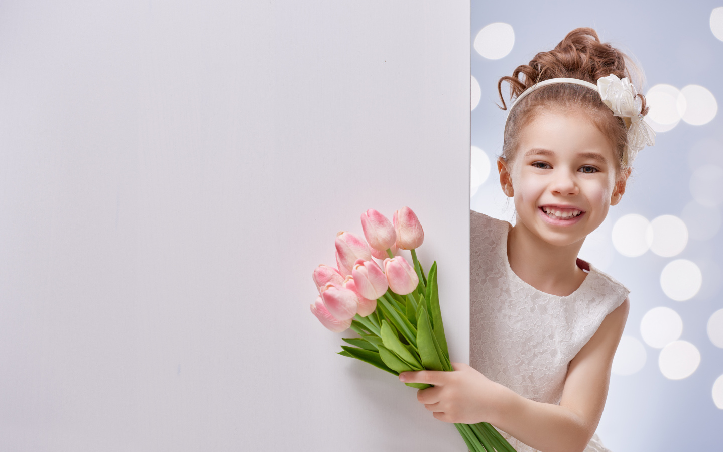 Улыбающаяся маленькая девочка с букетом розовых тюльпанов
