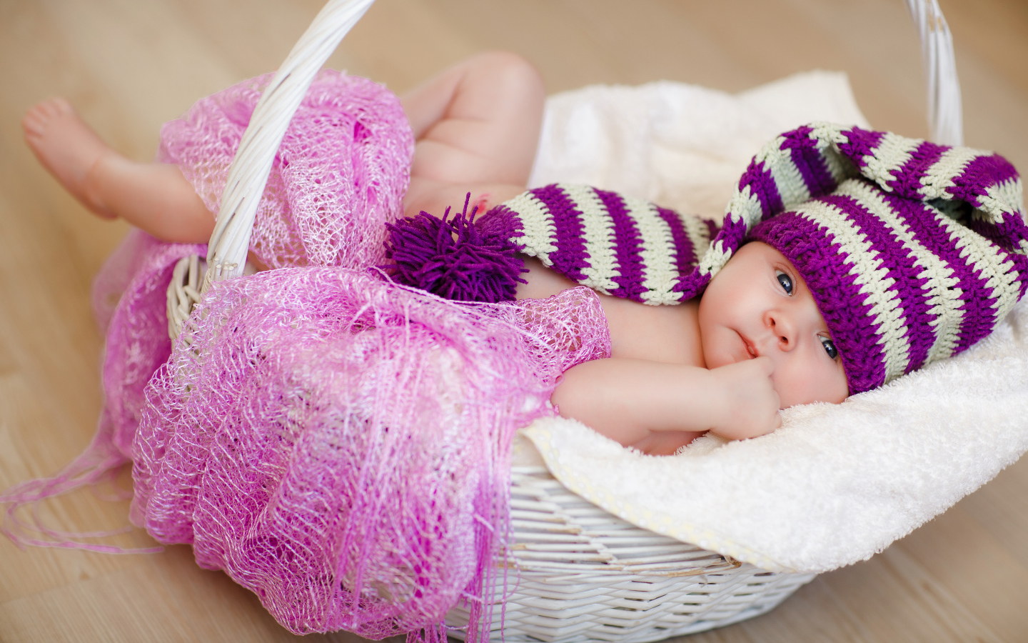 Младенец в красивой вязаной шапке лежит в корзине