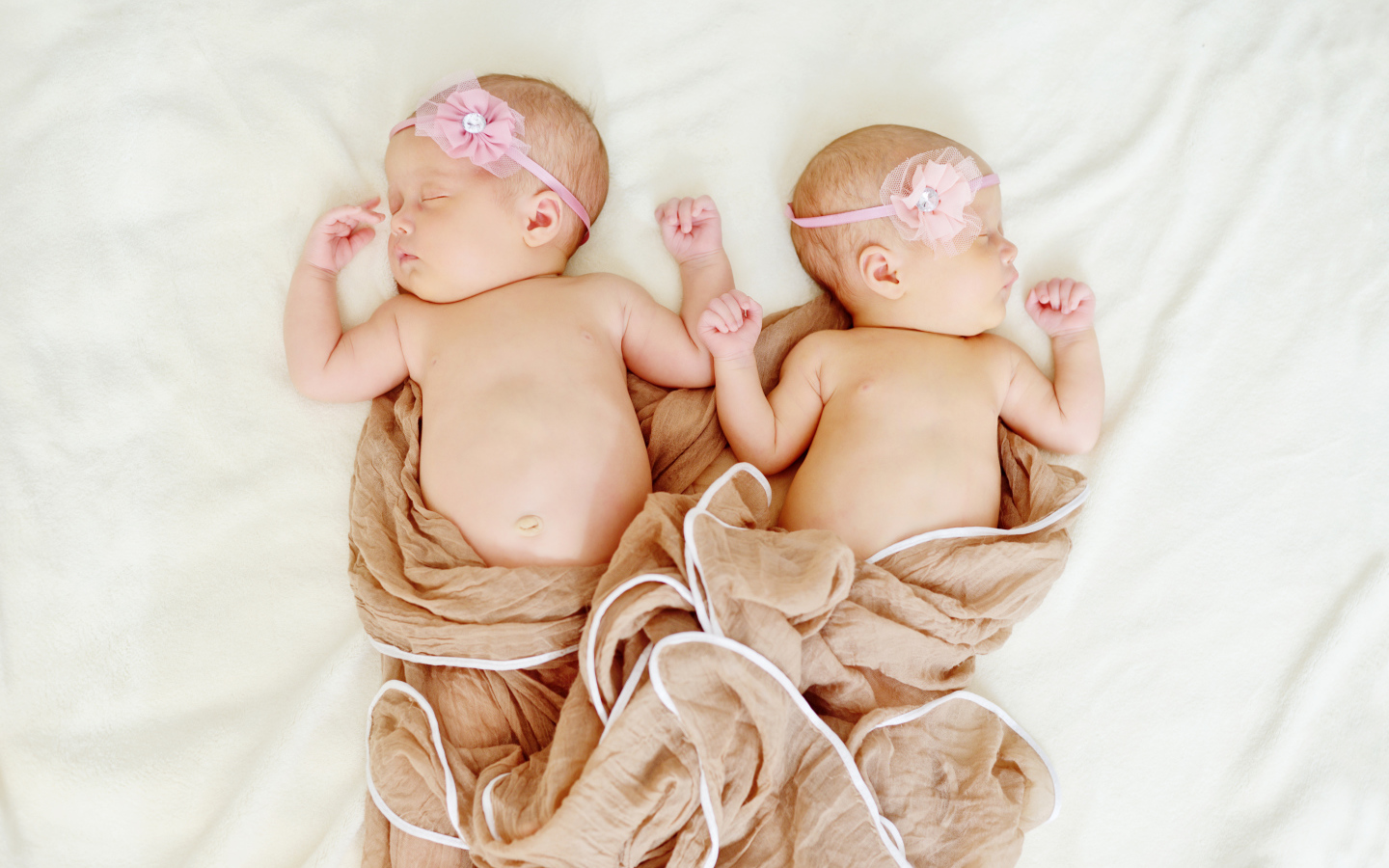 Два спящих младенца с розовыми цветами на голове