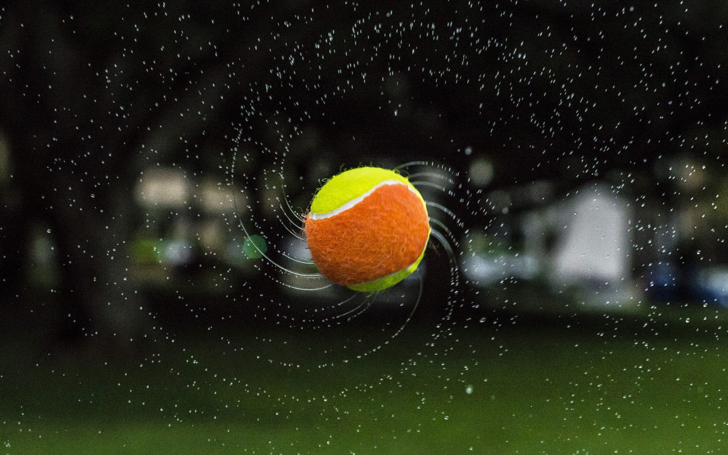 Теннисный мяч летит в каплях воды 