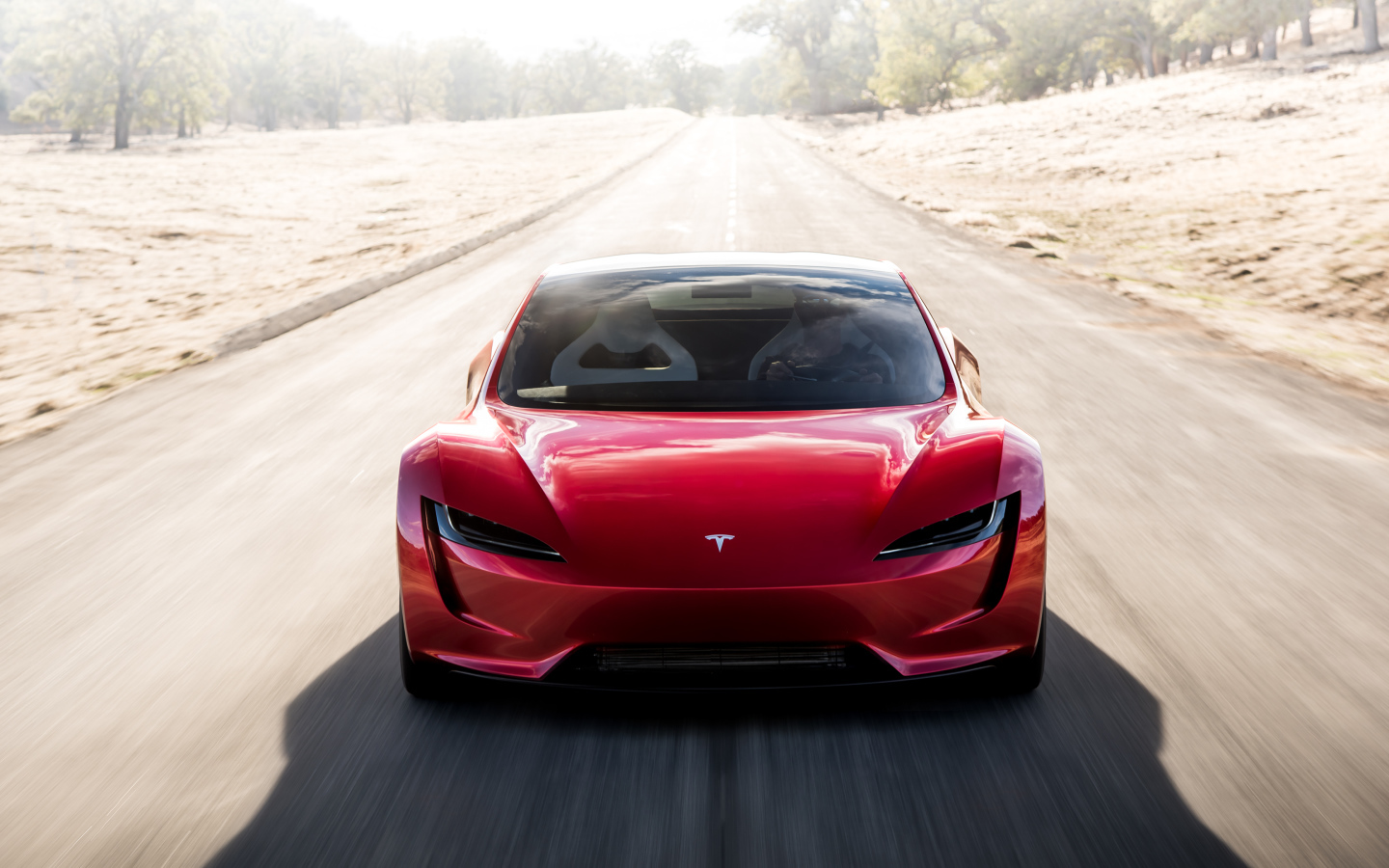 Красный автомобиль Tesla Roadster на трассе, вид спереди