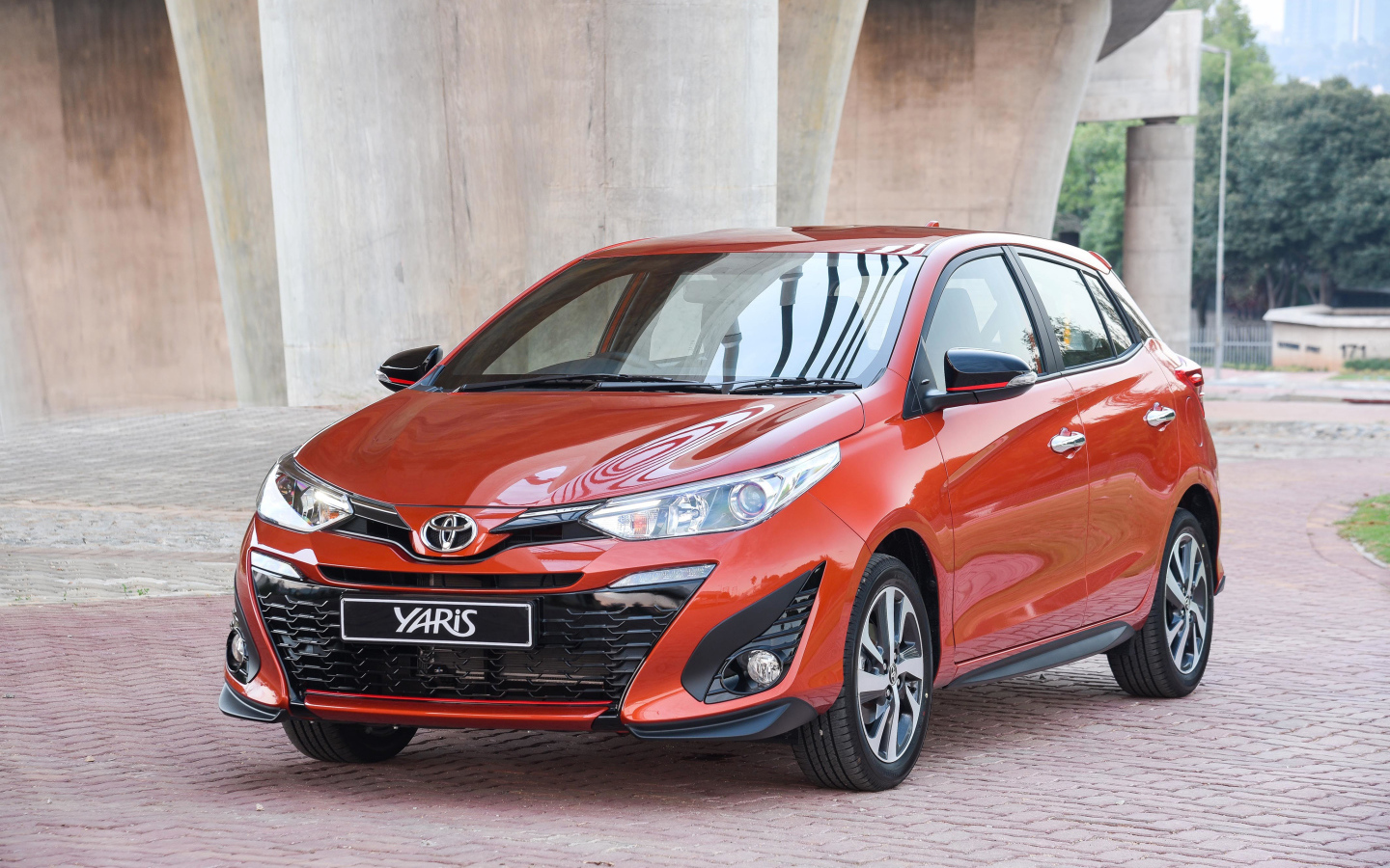 Красный автомобиль Toyota Yaris под мостом 