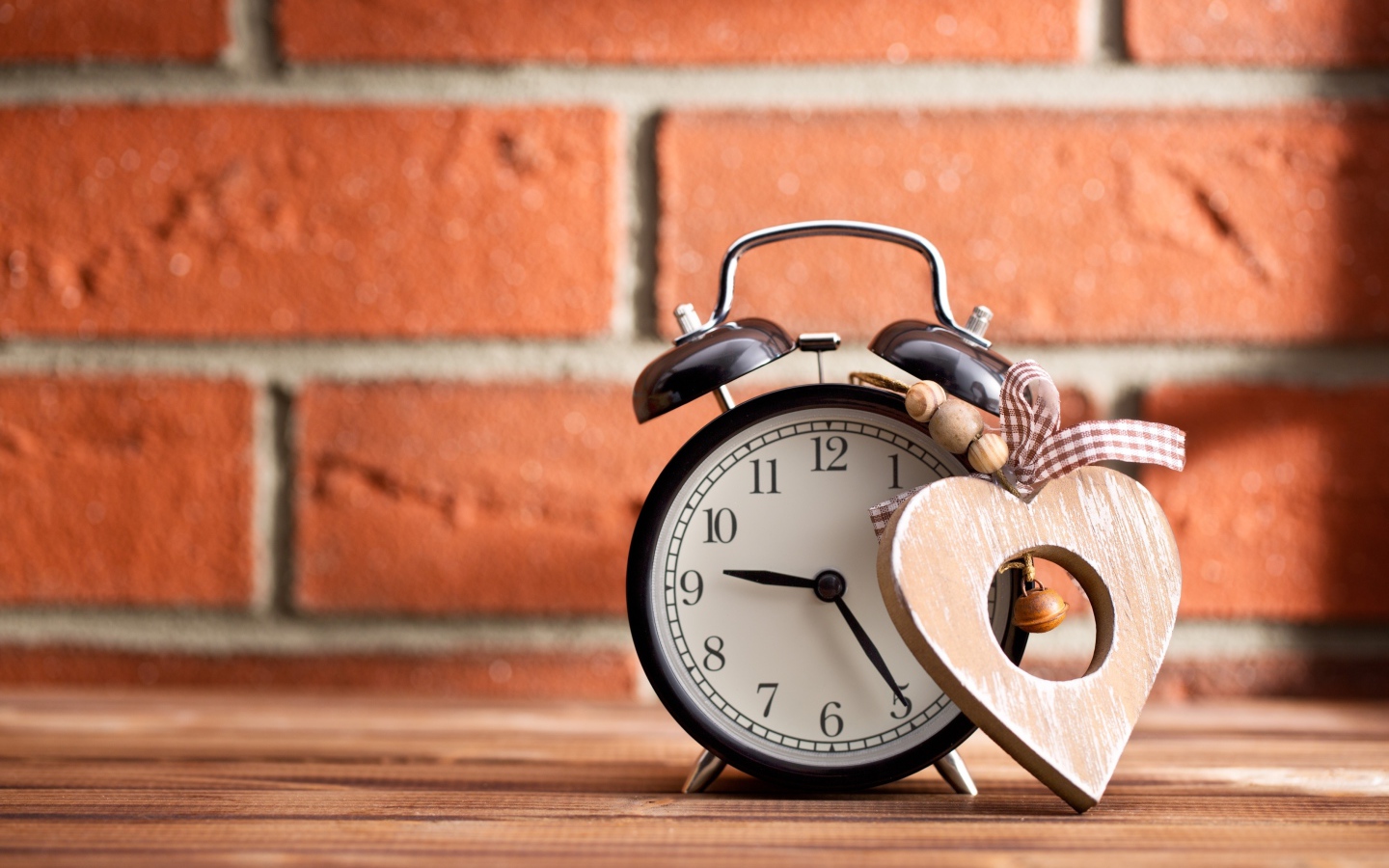 Будильник с деревянным сердцем стоит на фоне стены