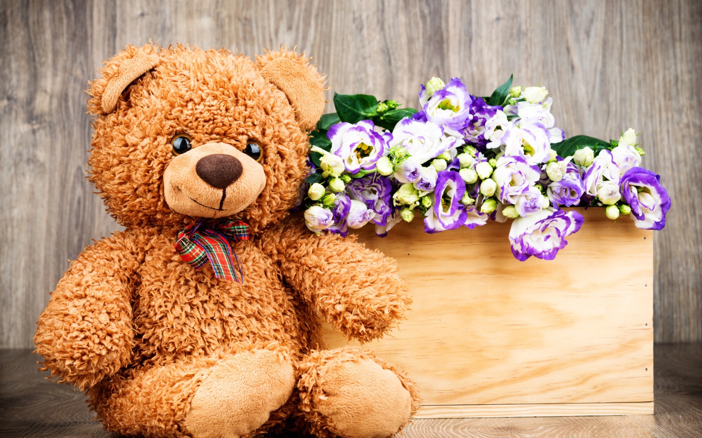 Плюшевый мишка с букетом цветов на деревянном фоне