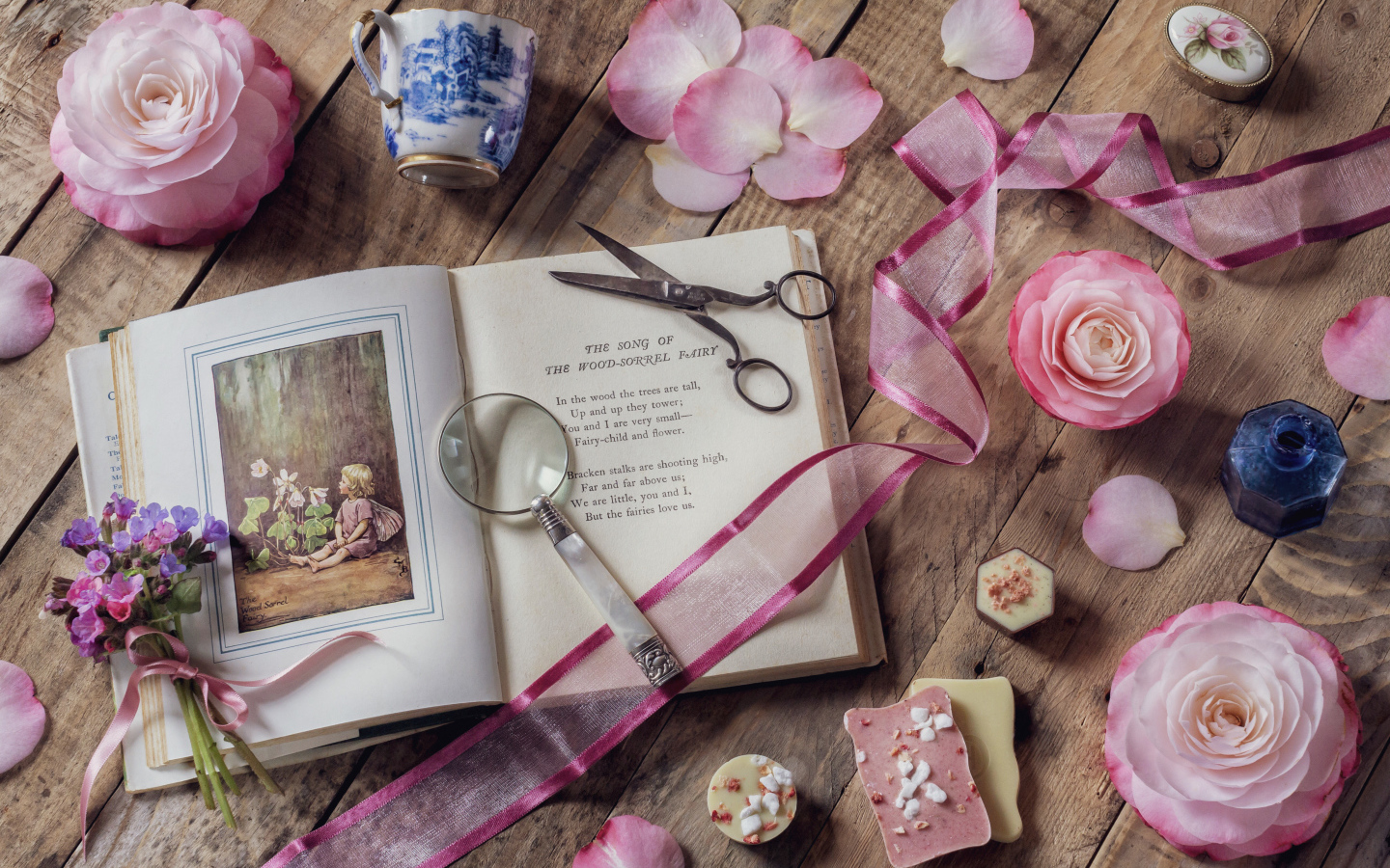 Старая книга на столе с увеличительным стеклом и искусственными цветами