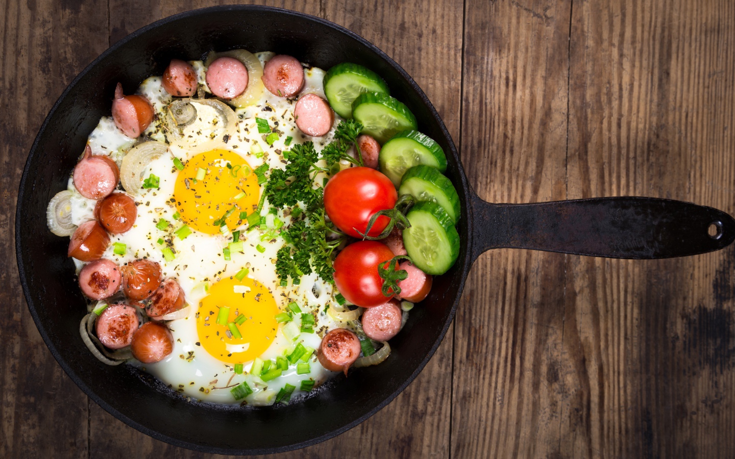 Яичница в сковороде с овощами и кусочками сосиски