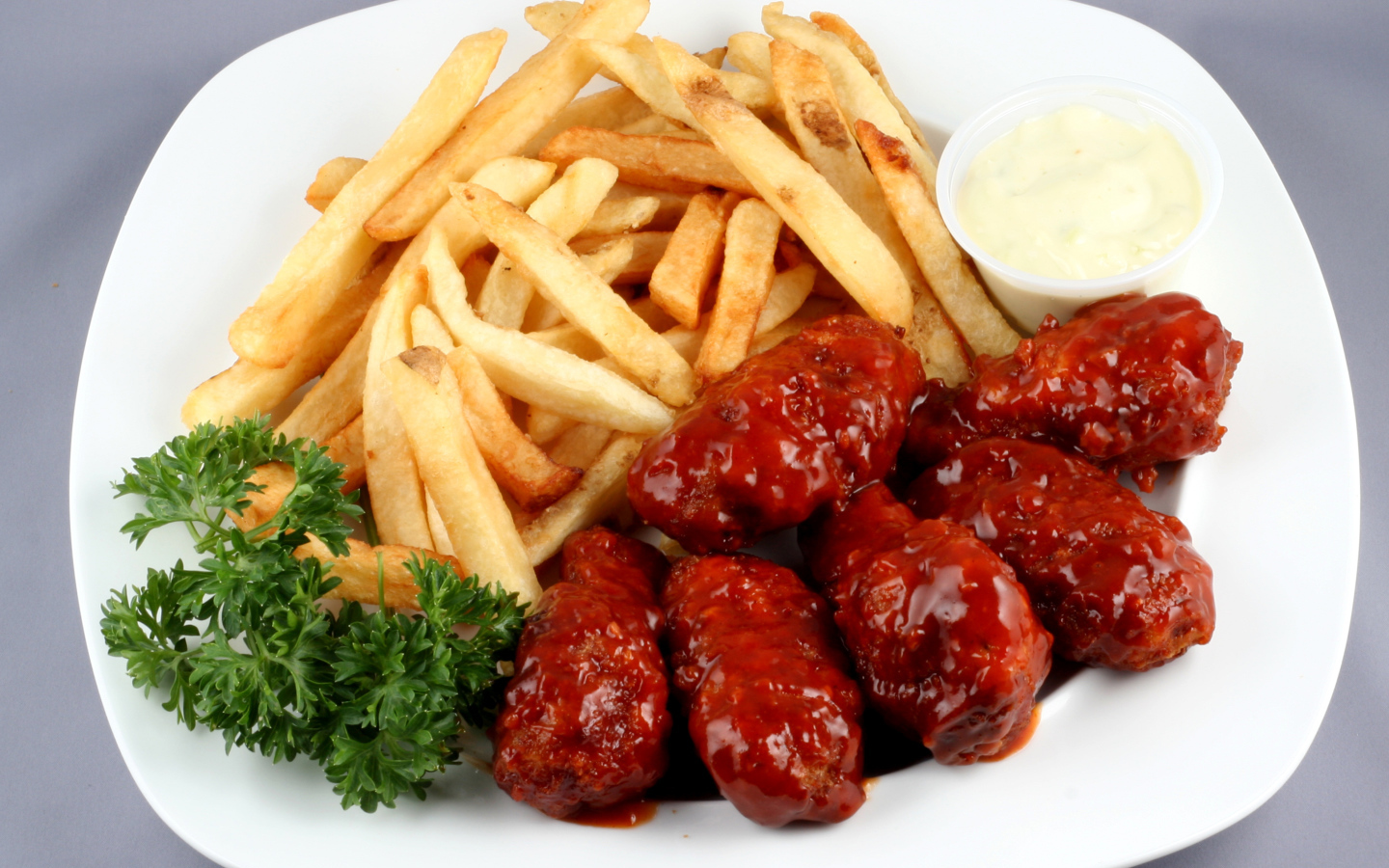 Тефтели в соусе с картофелем фри и петрушкой на тарелке