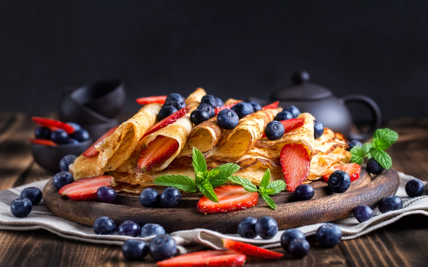 Блинчики с ягодами черники и клубники на столе