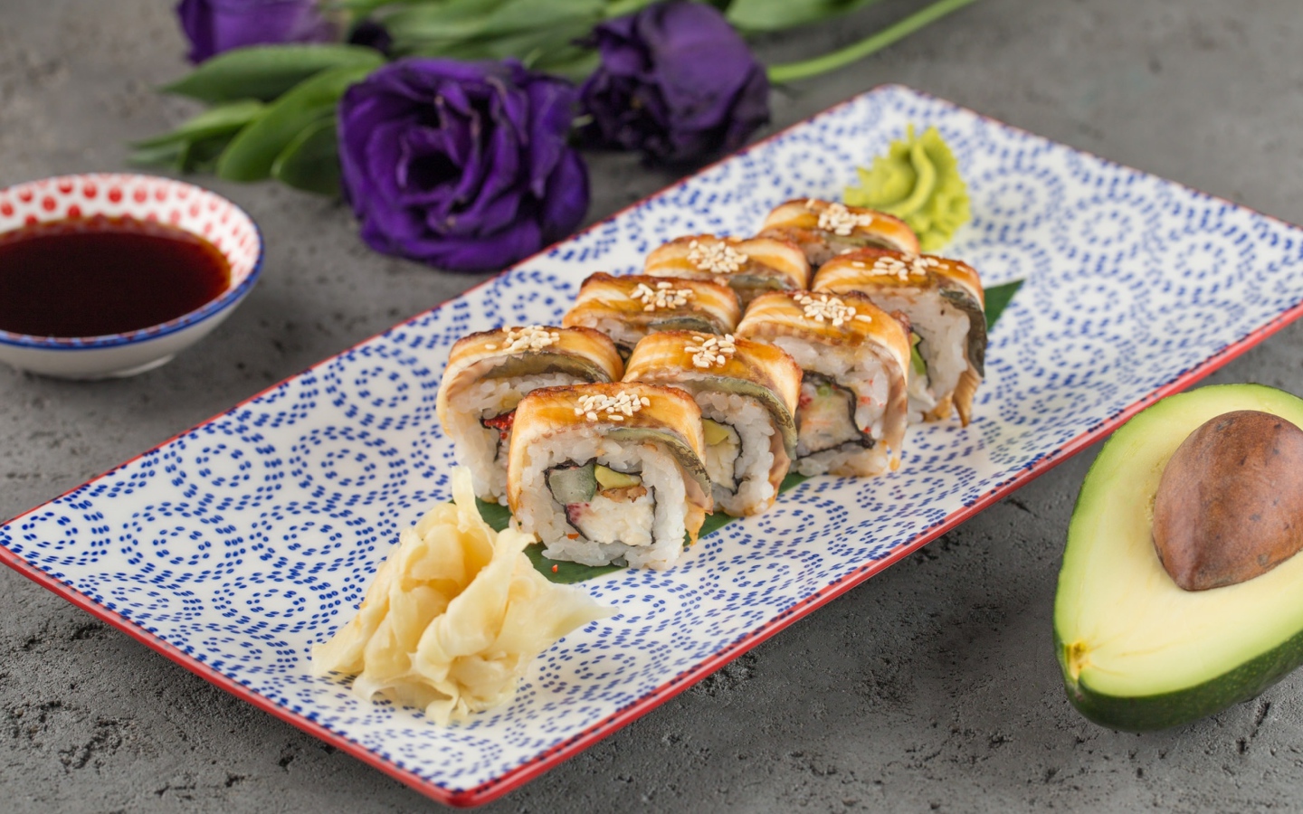 Роллы с авокадо и соевым соусом на столе с цветами 