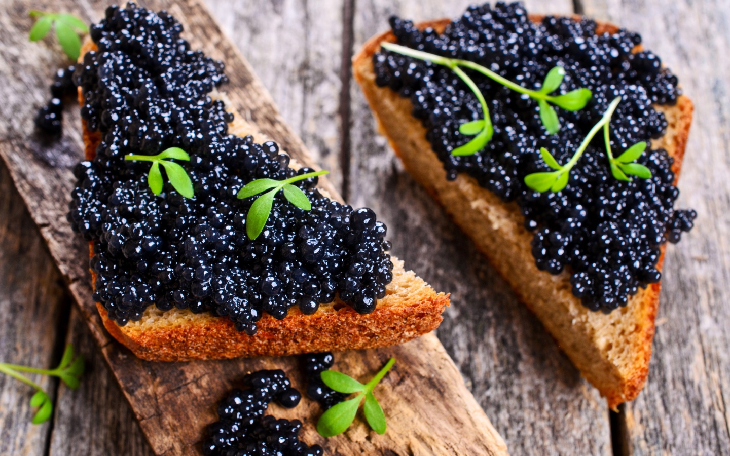 Два аппетитных бутерброда с черной икрой на деревянном столе