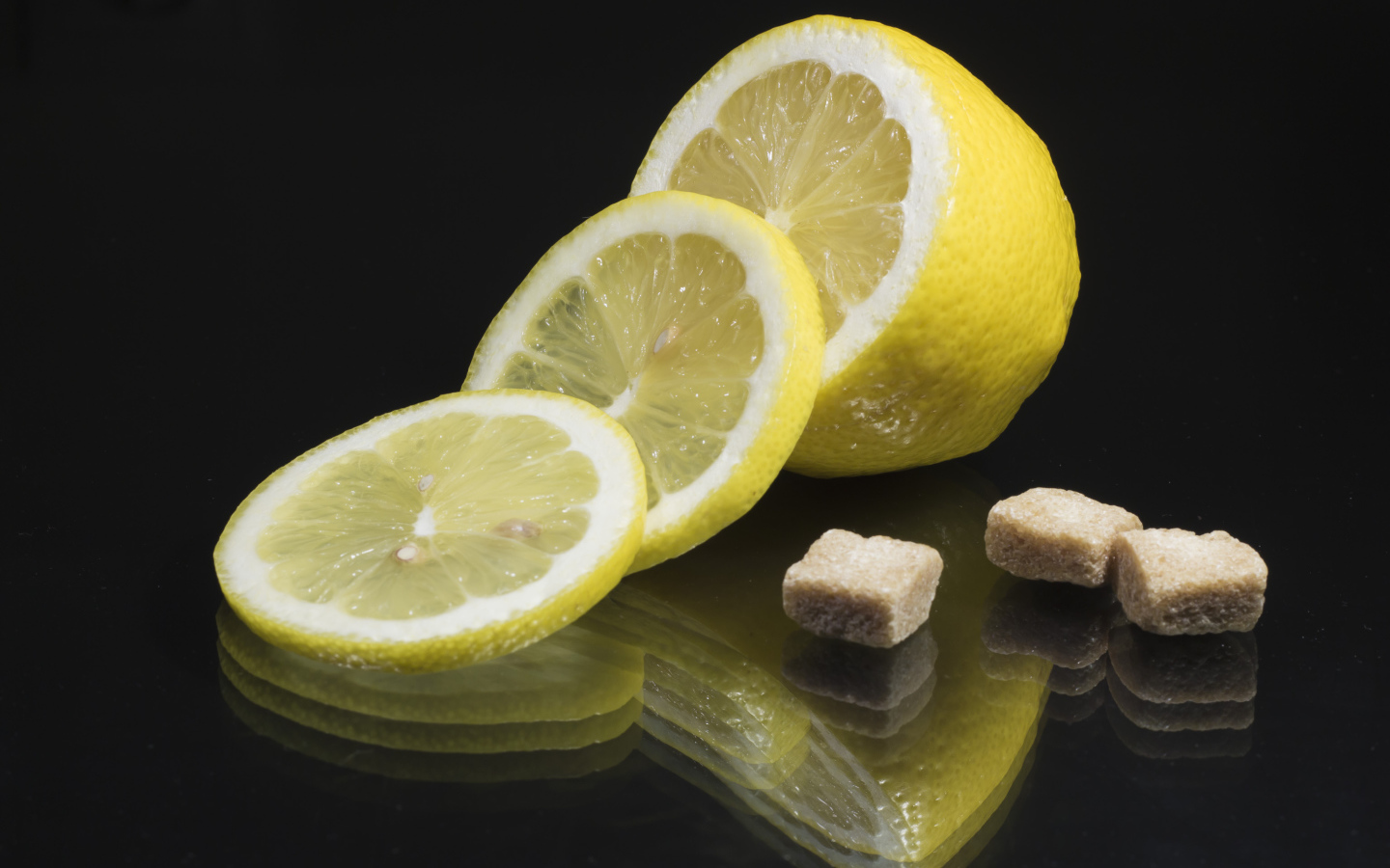 Нарезанный лимон с кусочками коричневого сахара на черном фоне