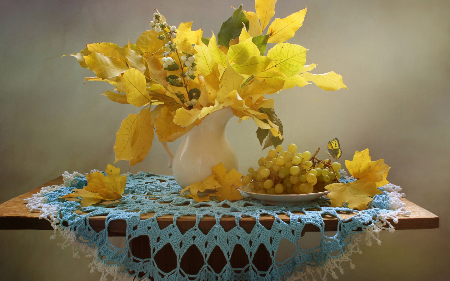 Белый виноград на столе с желтыми осенними листьями