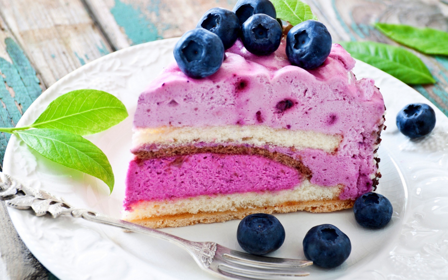 Торт с черничным муссом и свежими ягодами черники на белой тарелке 