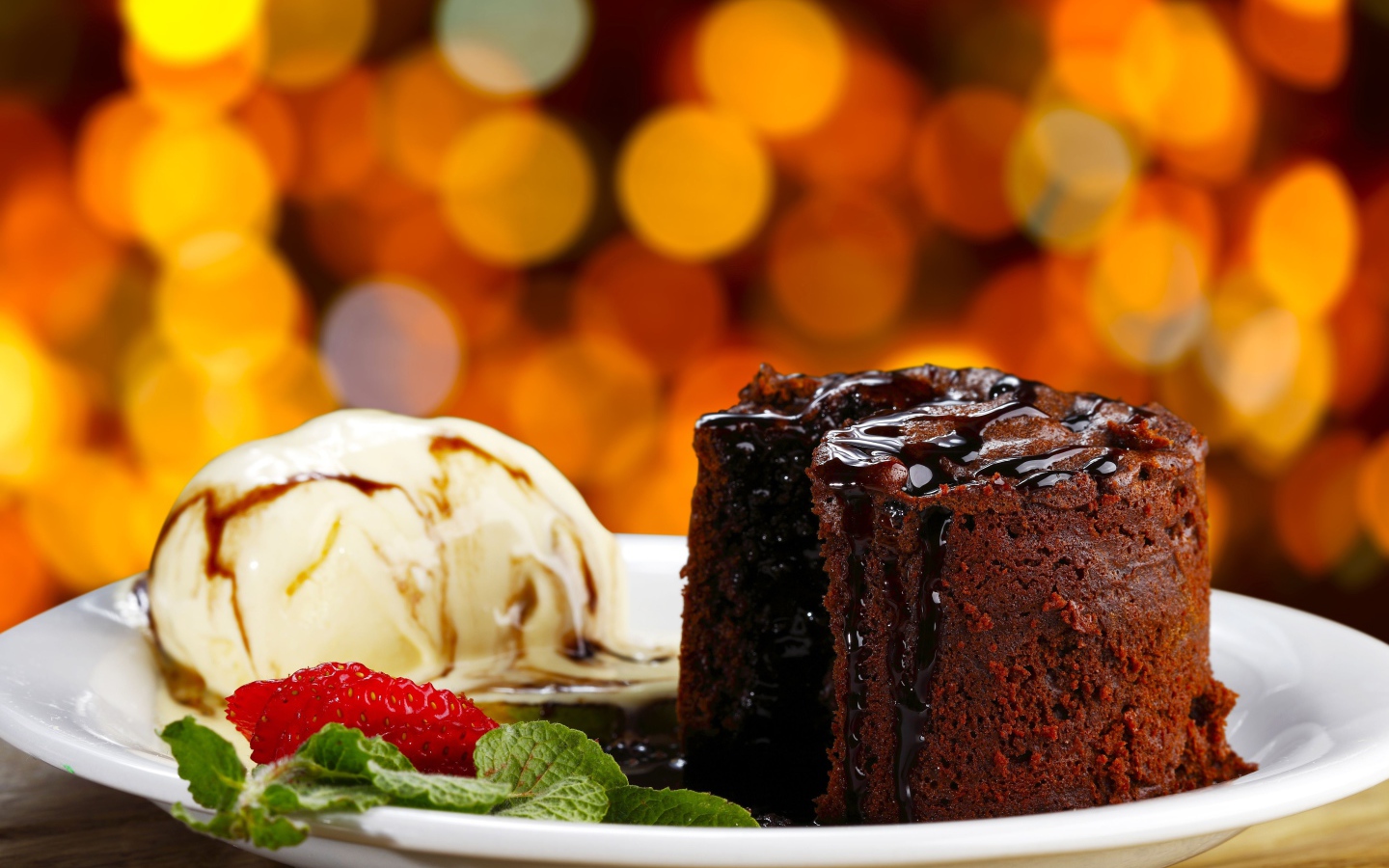 Шоколадное пирожное с мороженым и клубникой на тарелке