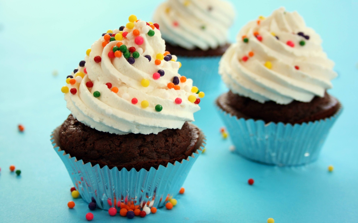 Шоколадные кексы со сливками и цветными брызгами на голубом фоне