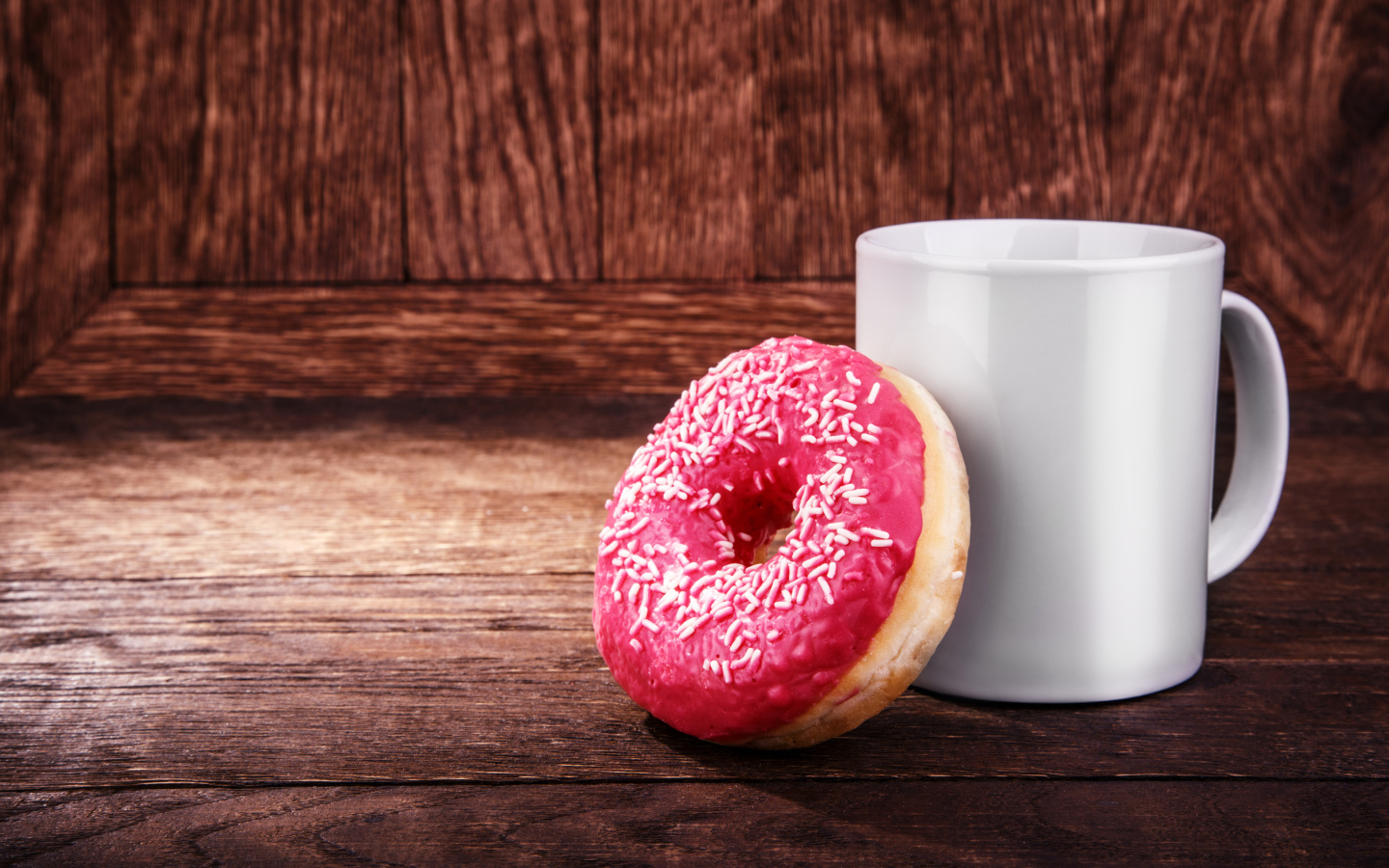 Пончик с белой кружкой на деревянном столе