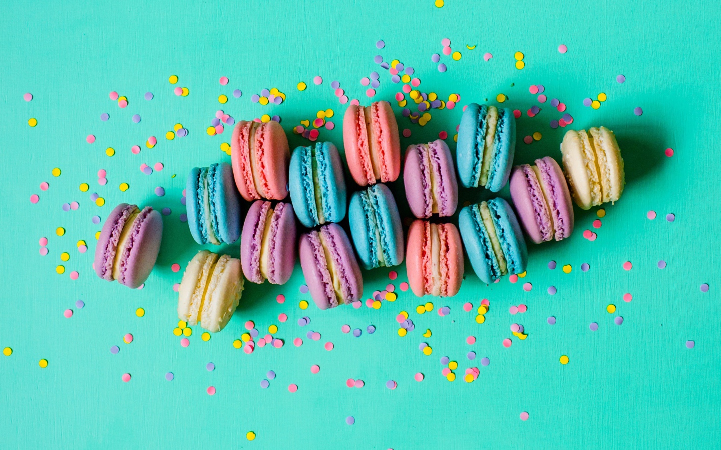Разноцветный десерт макарун на голубом фоне с конфетти
