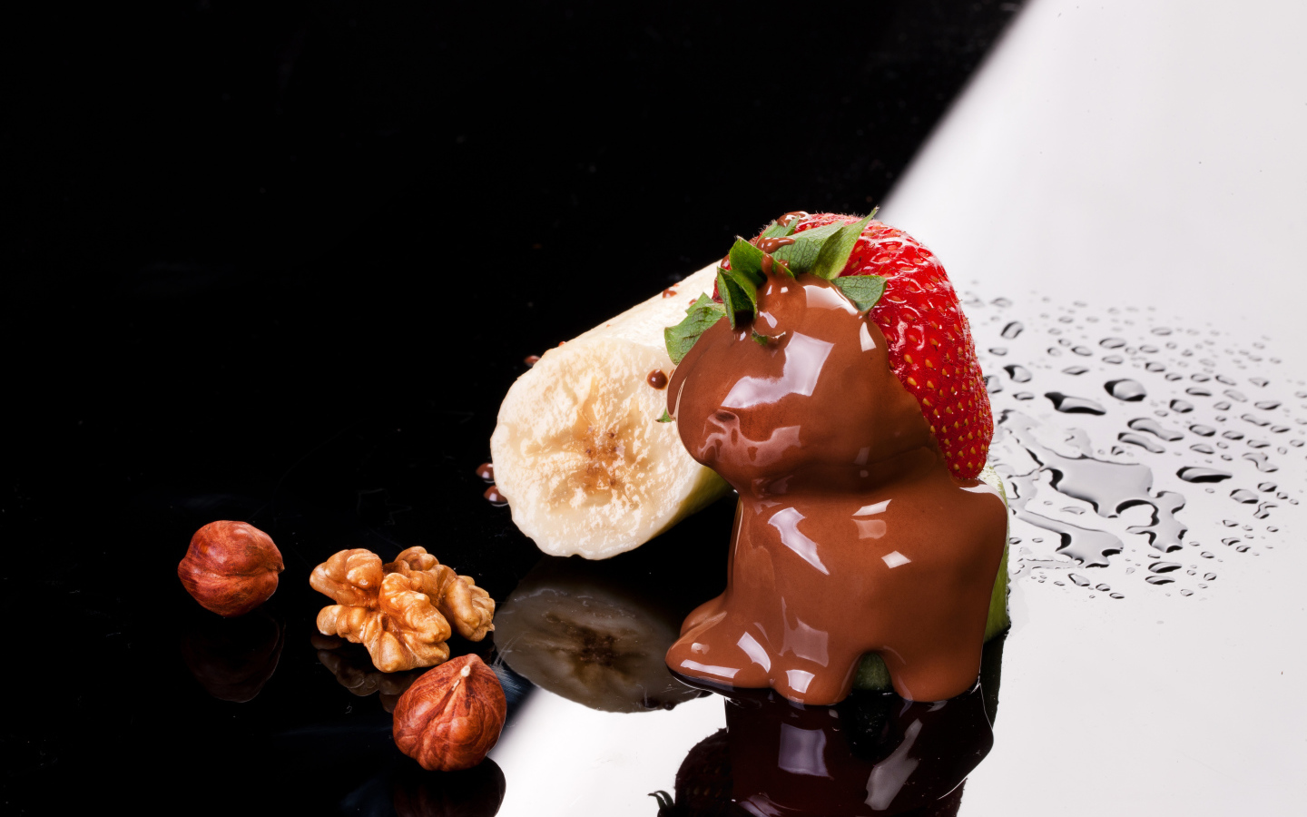 Клубника в шоколаде, банан и орехи на черной поверхности