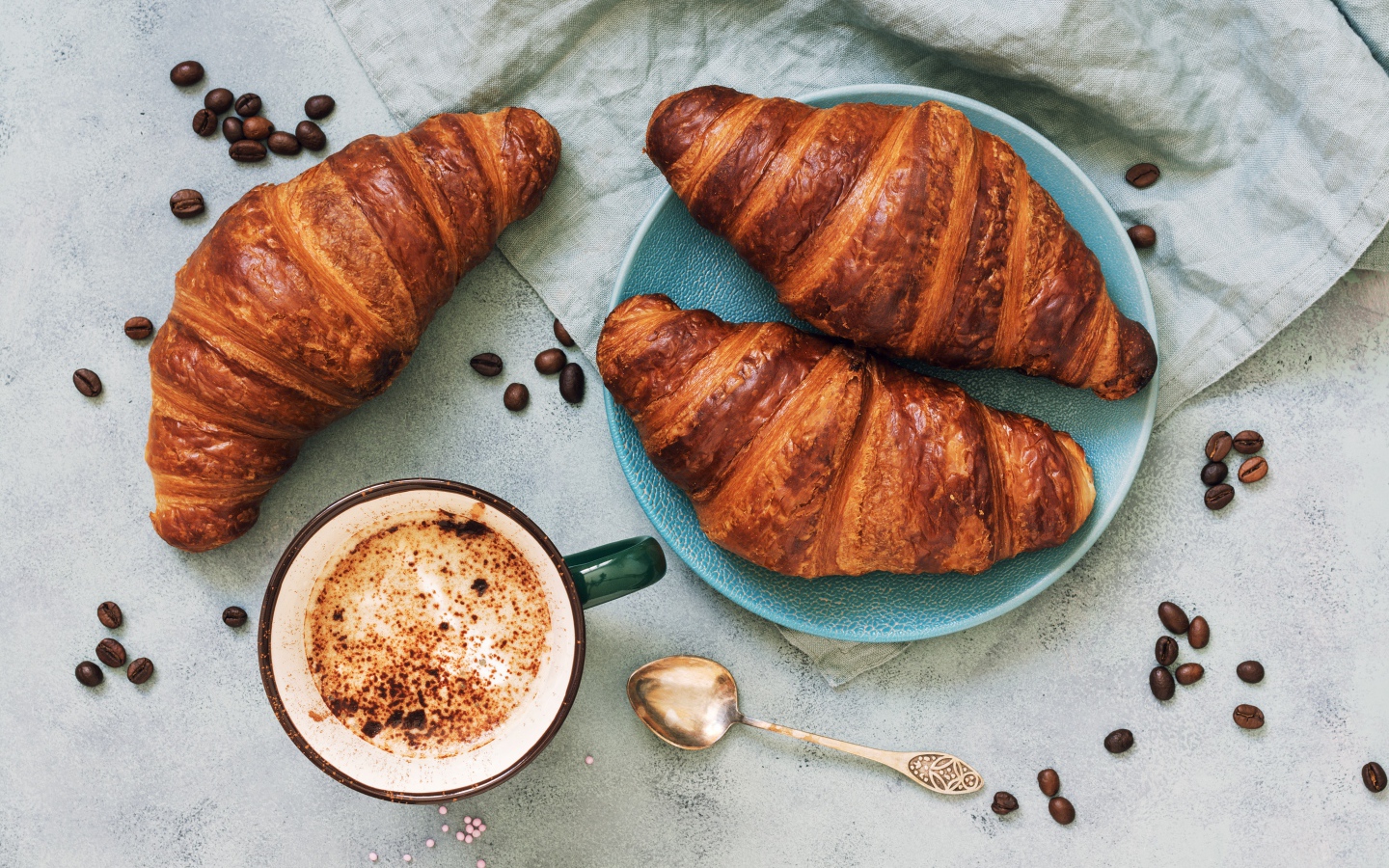 Три круассана на столе с чашкой кофе