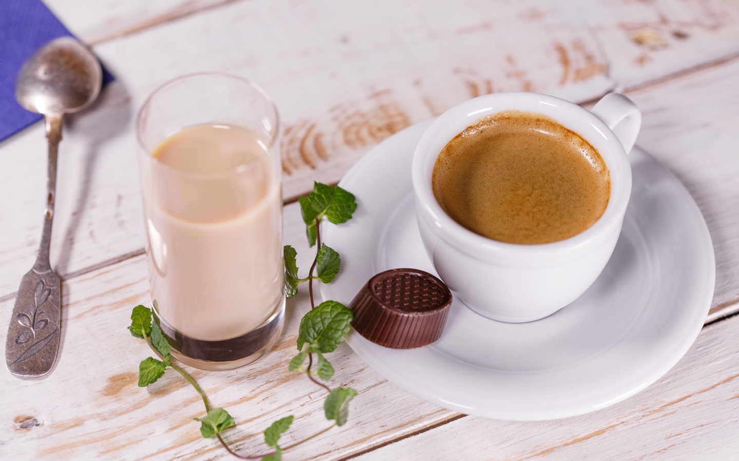 Чашка кофе с шоколадной конфетой и стаканом молока на столе