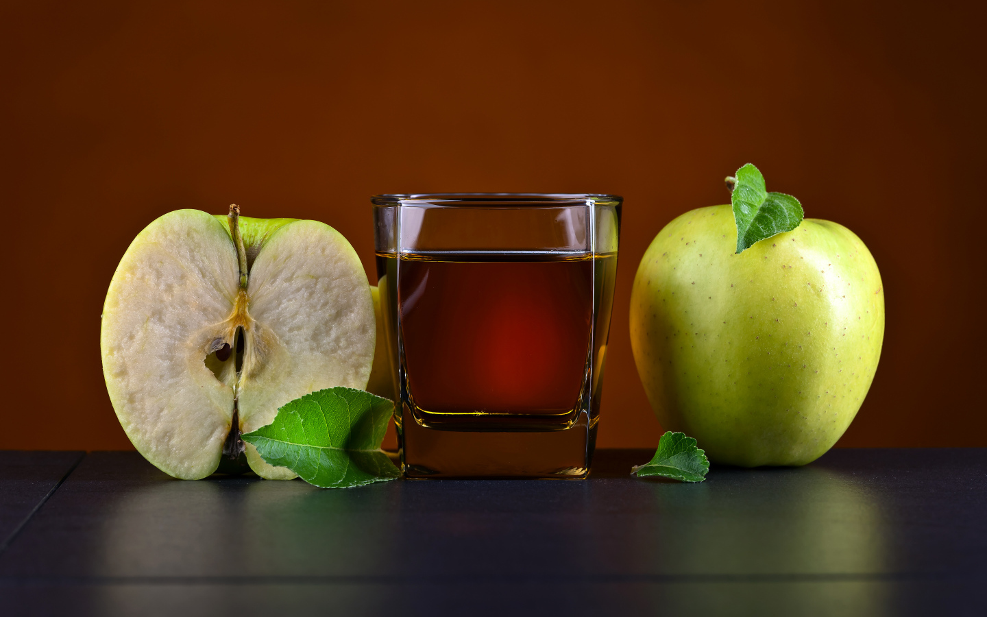 Стакан яблочного сока на столе с зелеными яблоками