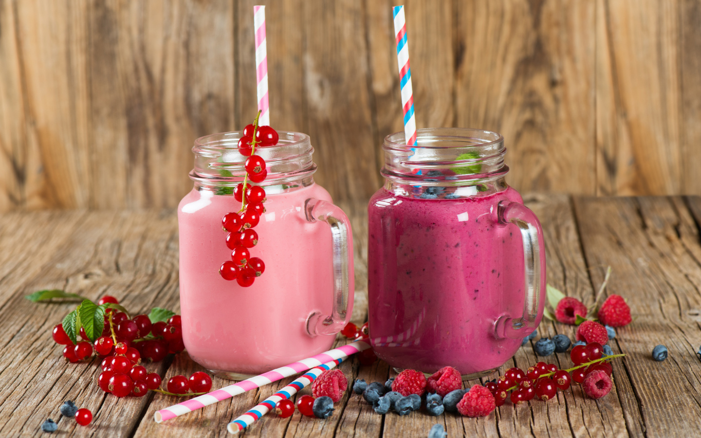 Ягодное смузи в баночках на столе со свежими ягодами малины, смородины и черники