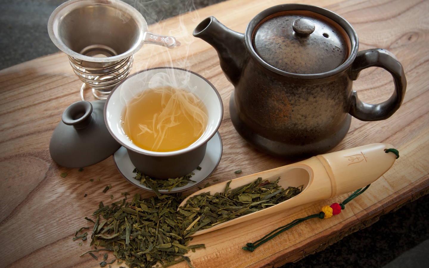 Свежий горячий чай на столе с чайными листьями и чайником